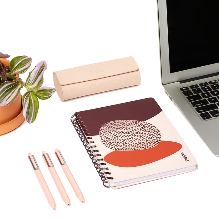 Desk with laptop, stylish notebooks, pens, and a potted plant on white (Blush)
