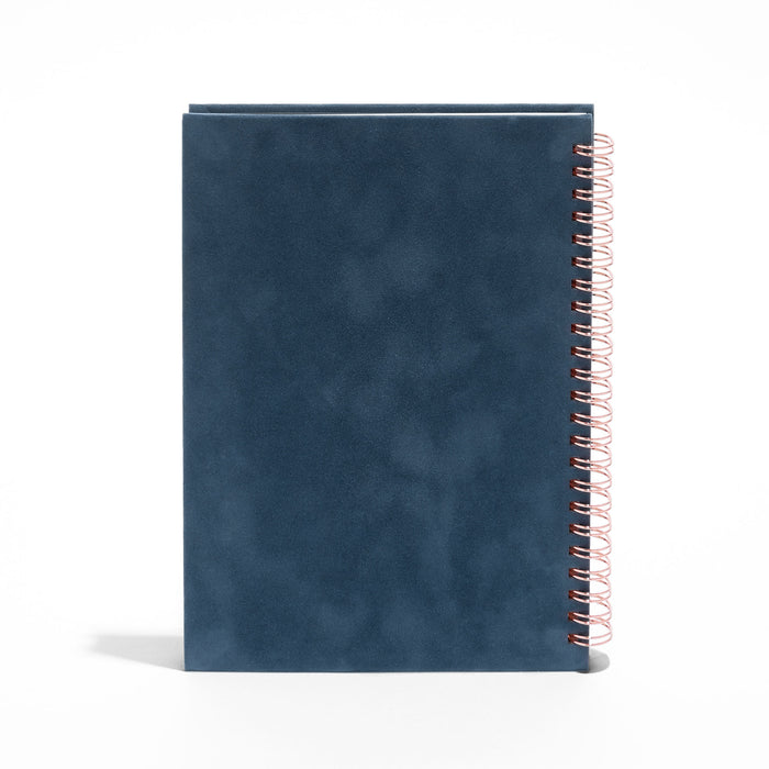 Blue spiral notebook with copper wire binding on a white background. (Storm)