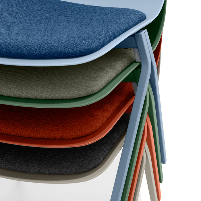 Stack of colorful modern chairs with cushioned seats on white background. (Brick)(Warm Gray)(Sky)(Sage)
