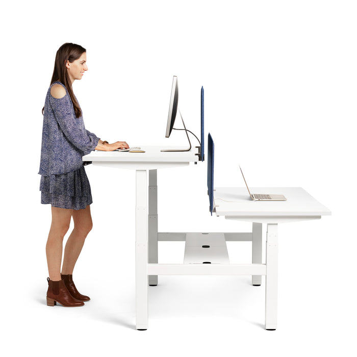 Woman standing and working at an adjustable height desk with a laptop and monitor. (White-57&quot;)(White-47&quot;)