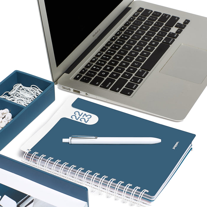 Laptop with earphones and a blue notebook with a pen on a white desk (Slate Blue)