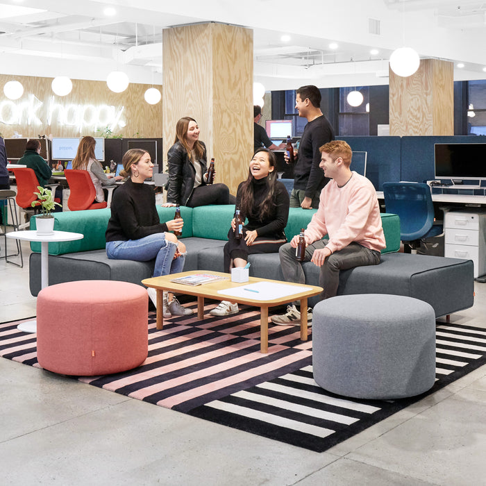 Modern office lounge area with employees engaging in casual conversation. (Blue)(Dark Blue)(Dark Gray)(Grass)(Gray)(Rose)