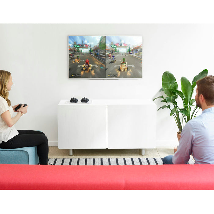 Two people playing a racing video game on a TV in a modern living room. (White)