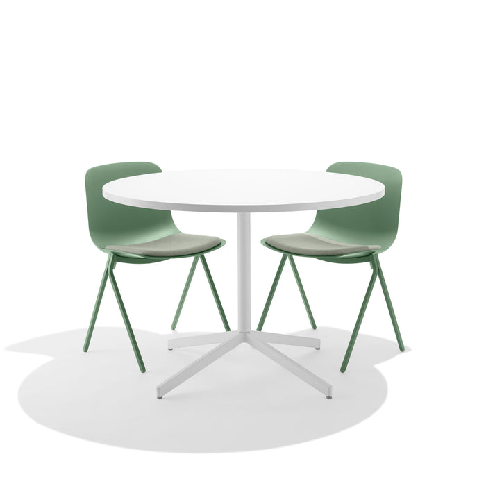 Round white table with green chairs on white background. (Sage)