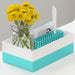 Yellow flowers in a glass jar and turquoise stationary holder on a desk. (Aqua)