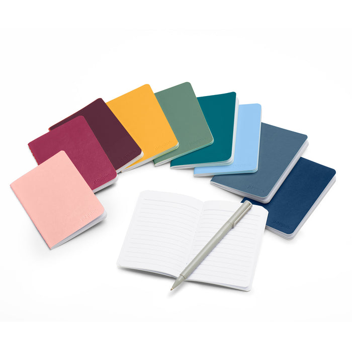 Colorful assortment of closed notebooks with one open notebook and pen on white background. 