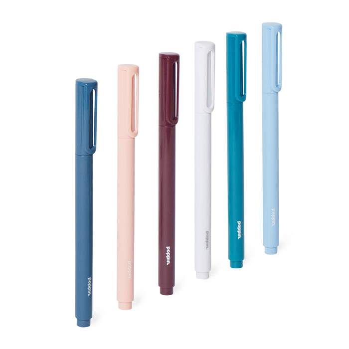 Assortment of sleek modern pens in navy, coral, burgundy, white, and sky blue on white background. 