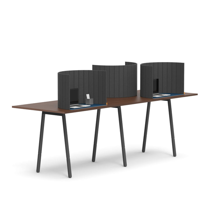 Modern wooden desk with partitions and laptops in office setting. 
