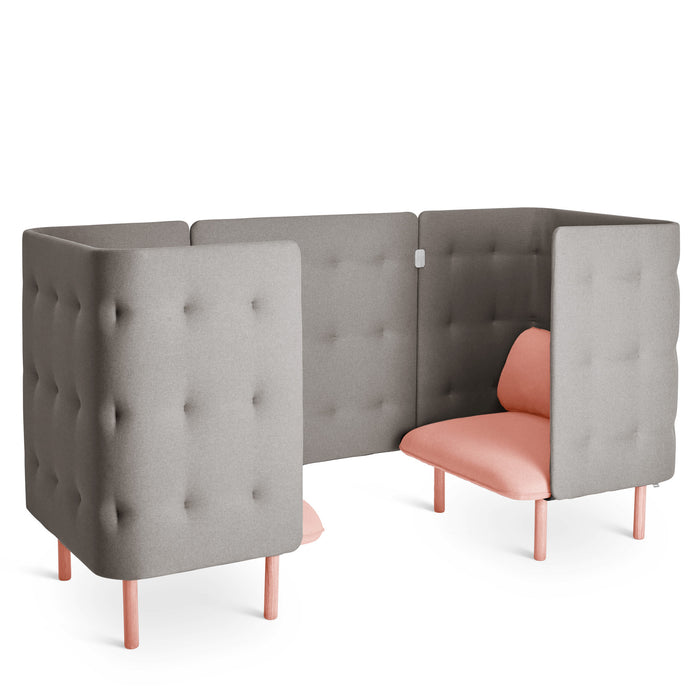 Modern grey upholstered privacy booth with pink cushions and wooden legs against a white background. (Blush-Gray)