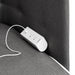 Portable white power bank with cable on gray sofa fabric. 
