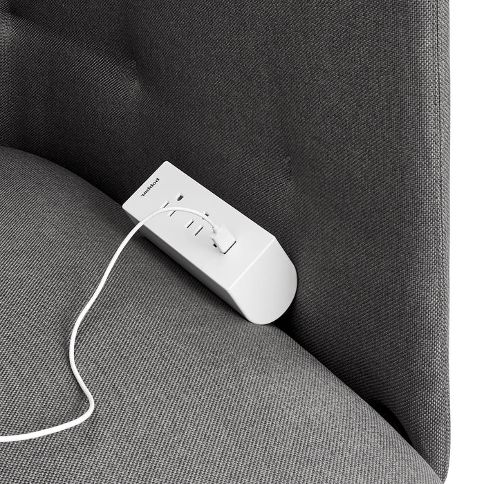 White remote control on a gray fabric sofa with a visible cable. 