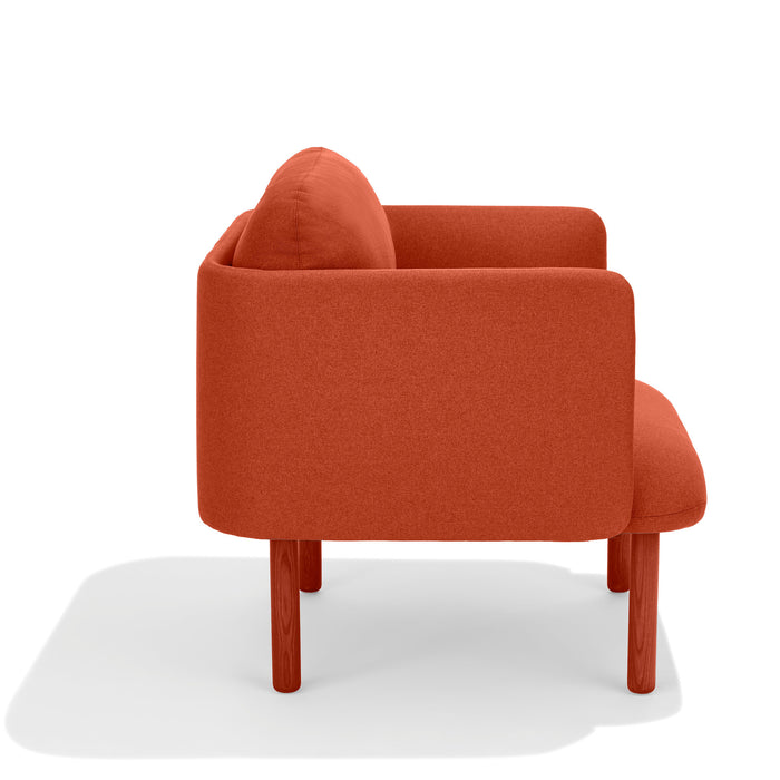 Modern red fabric armchair with wooden legs on a white background. (Brick)