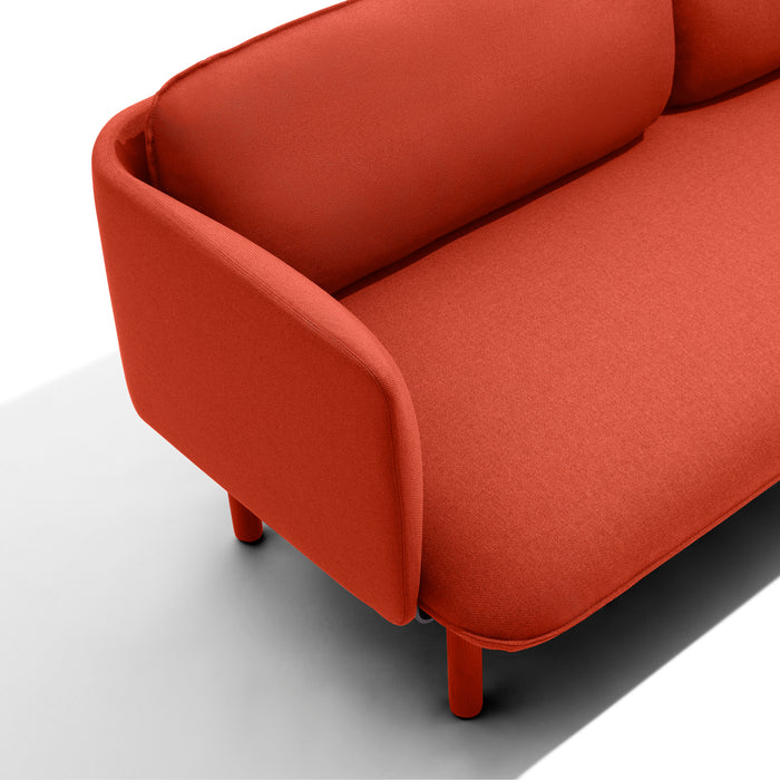 Modern red fabric sofa on a white background with wooden legs. (Brick)