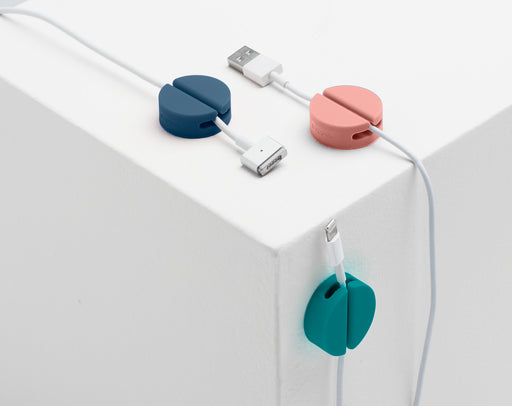 Cable organizers on white ledge with USB, Lightning, and charger cables in pink, blue, and green. (Contemp. Assorted)