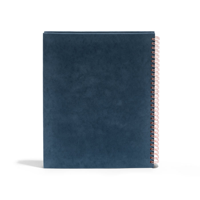 Blue spiral notebook with copper wire binding on white background. (Storm)