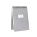 Spiral-bound grey notebook standing upright on white background. (Light Gray)