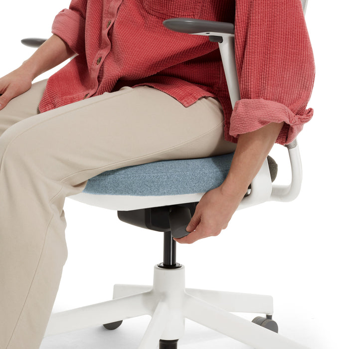 Person adjusting ergonomic office chair height, focus on chair adjustment lever. (Dorset Sea-White)