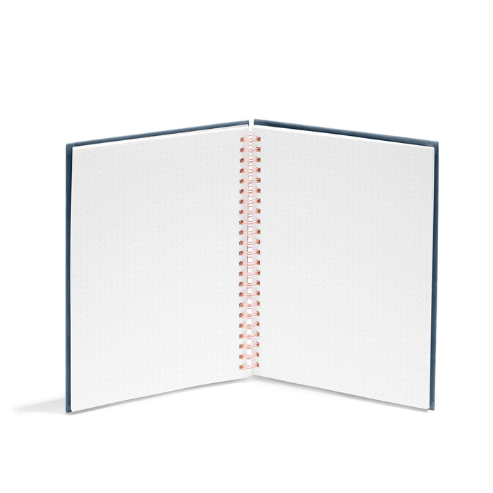 Open spiral notebook with blank pages on white background. (Storm)