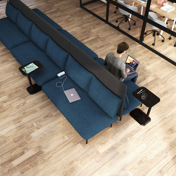Man working on laptop on blue sectional sofa in modern home office setting. (Dark Gray-Dark Gray)(Brick-Dark Gray)(Dark Blue-Dark Gray)(Teal-Dark Gray)(Gray-Gray)(Blush-Gray)(Brick-Gray)(Dark Blue-Gray)