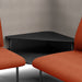 Black modern coffee table between two orange chairs on a grey background. (Brick-Gray)