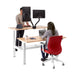 Two professionals working at a modern standing desk with dual monitors and ergonomic chairs. (Natural Oak-57&quot;)