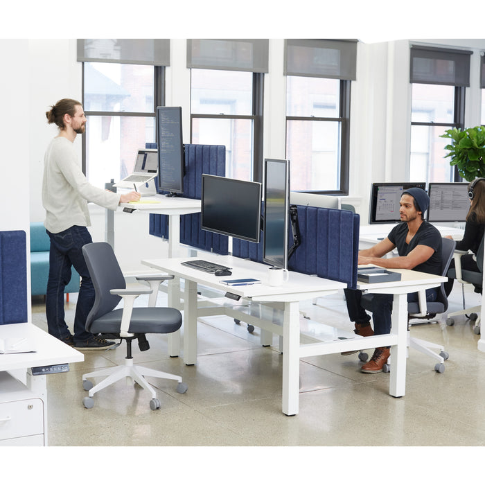 Man standing at a modern standing desk workstation in a bright office setting. (White-57&quot;)(White-47&quot;)