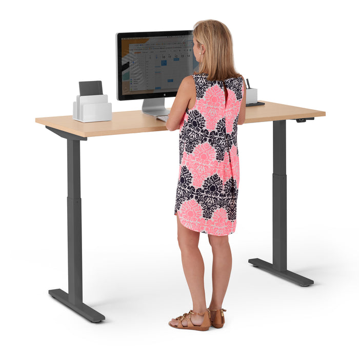 Woman standing at adjustable height desk with computer and printer. (Natural Oak-57&quot;)