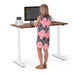 Woman standing at adjustable standing desk working on computer in modern office. (Walnut-47&quot;)