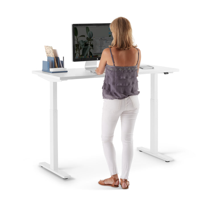 Woman standing at a modern white standing desk working on a computer (White-47&quot;)