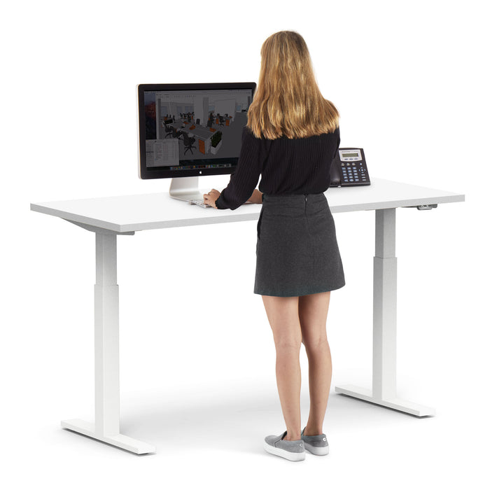 Woman standing at a modern height-adjustable desk using a computer. (White-60&quot;)