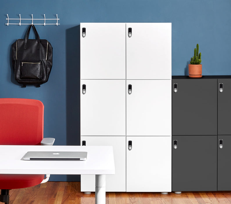 Modern office interior with white and gray storage lockers, red chair, laptop on desk, plant, and backpack. (Charcoal)(White)