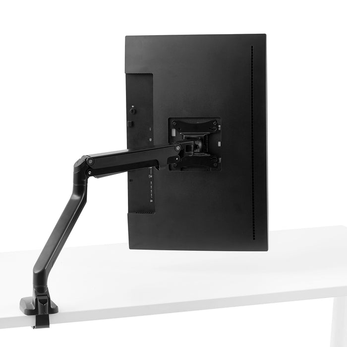 Back view of a mounted flat-screen monitor with adjustable arm on a white desk. (Black)