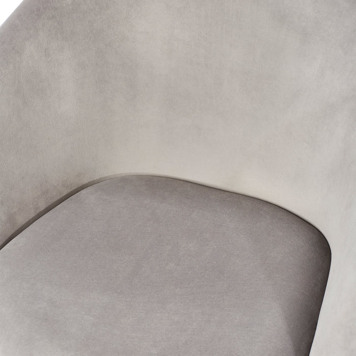 Close-up of a modern grey velvet chair with a curved backrest. (Gray)