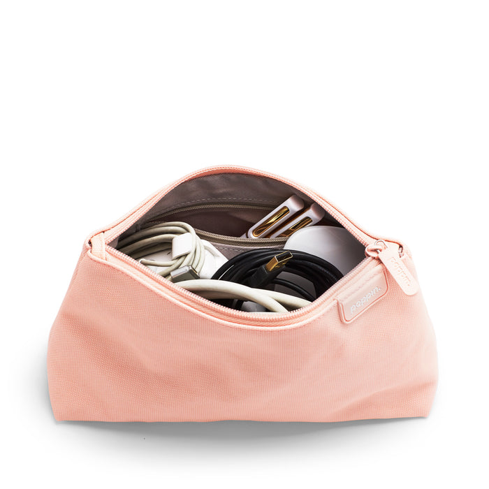 Pink travel organizer bag open with electronic accessories inside on white background. (Blush)