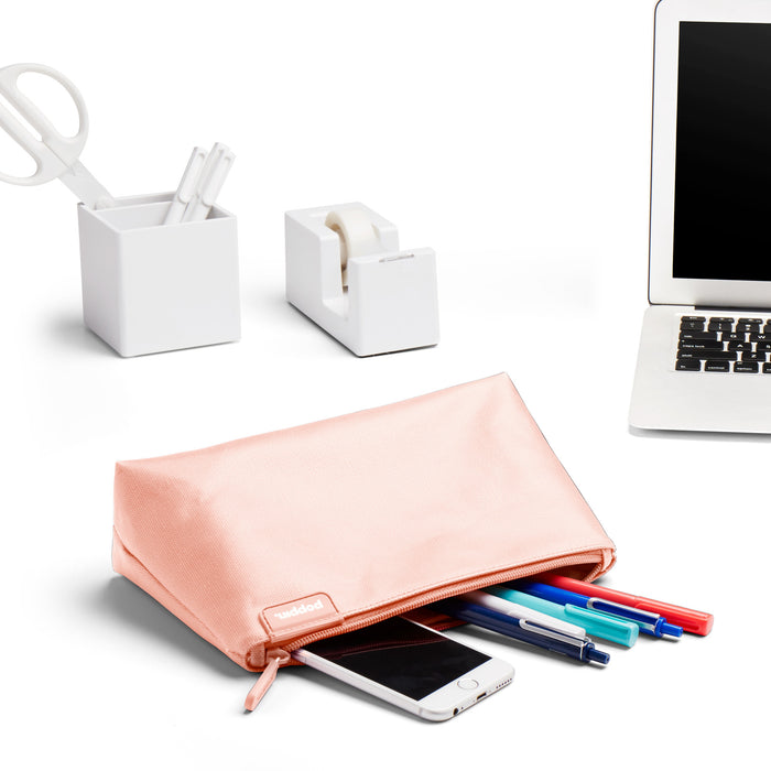 "Clean office desk with MacBook, smartphone, stationery holders, and peach pencil case on white background." (Blush)