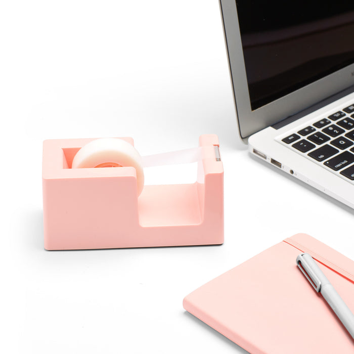 Pink tape dispenser next to laptop and notebook on white background (Blush)