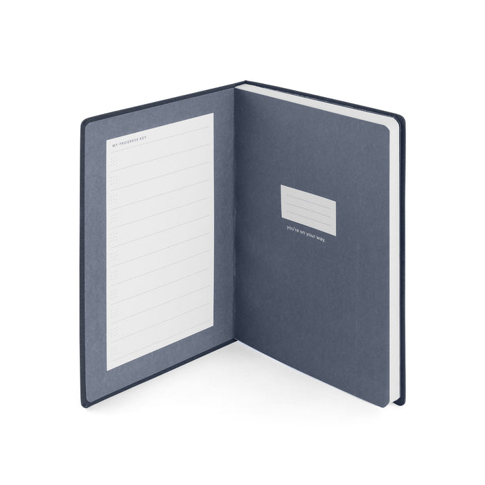 Open navy blue notebook with lined pages on a white background. (Lagoon)