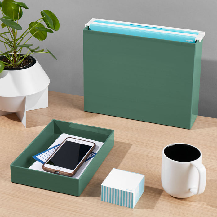Office desk with green organizer, smartphone, notepad, plant, and coffee mug. (Sage)