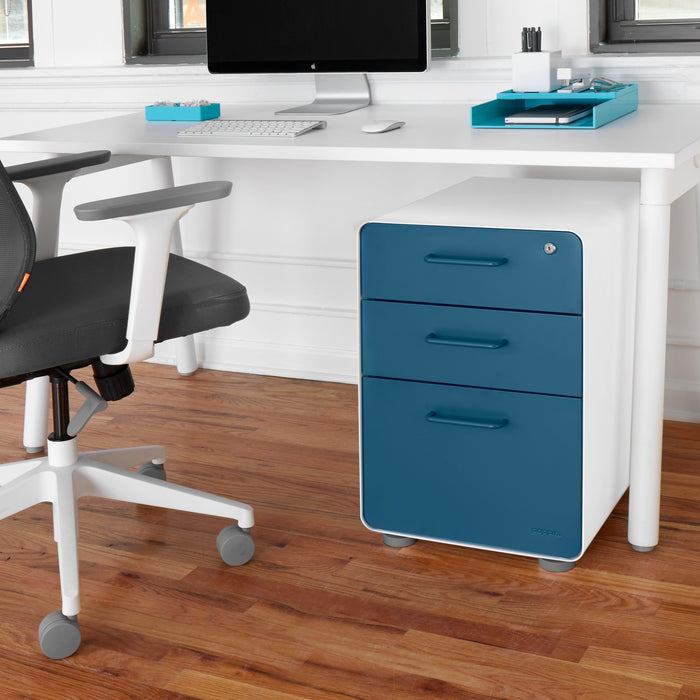 Modern home office with white desk, ergonomic chair, and blue filing cabinet. (Slate Blue-White)