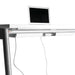 Modern standing desk with a laptop docked on top and cables neatly arranged. (White)