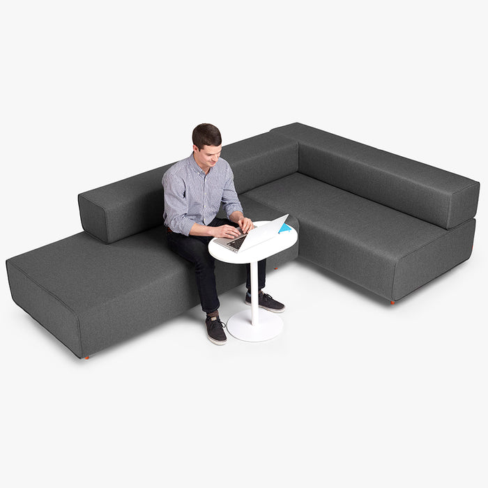 Man working on laptop at modern sectional sofa with small white table. (Dark Gray-Dark Gray)(Dark Blue-Dark Blue)(Dark Gray-Dark Blue)