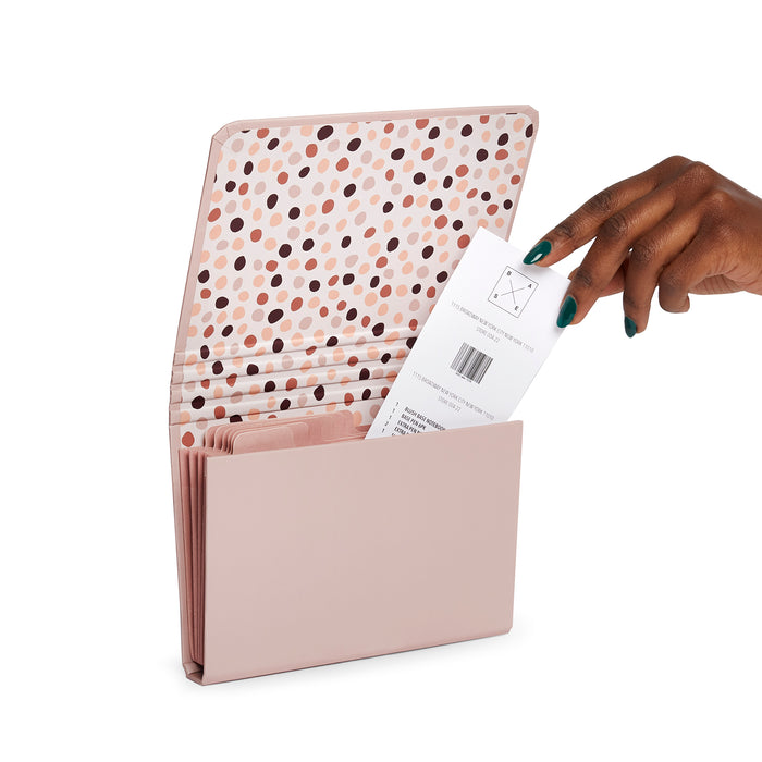 Hand inserting a document into a modern pink desk organizer with polka dot pattern. 