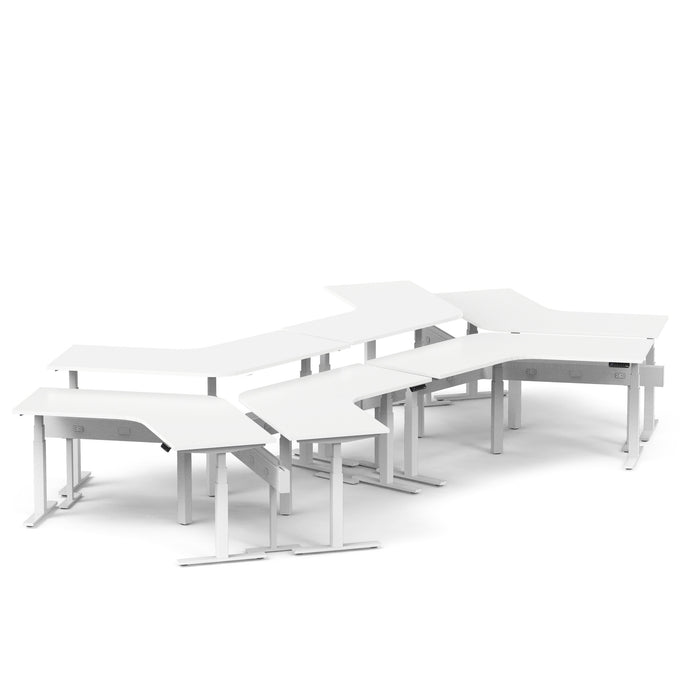 Modular office desks in white arranged in a dynamic layout on a plain background. 