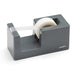 Gray desktop tape dispenser with roll of clear adhesive tape on white background. (Dark Gray)