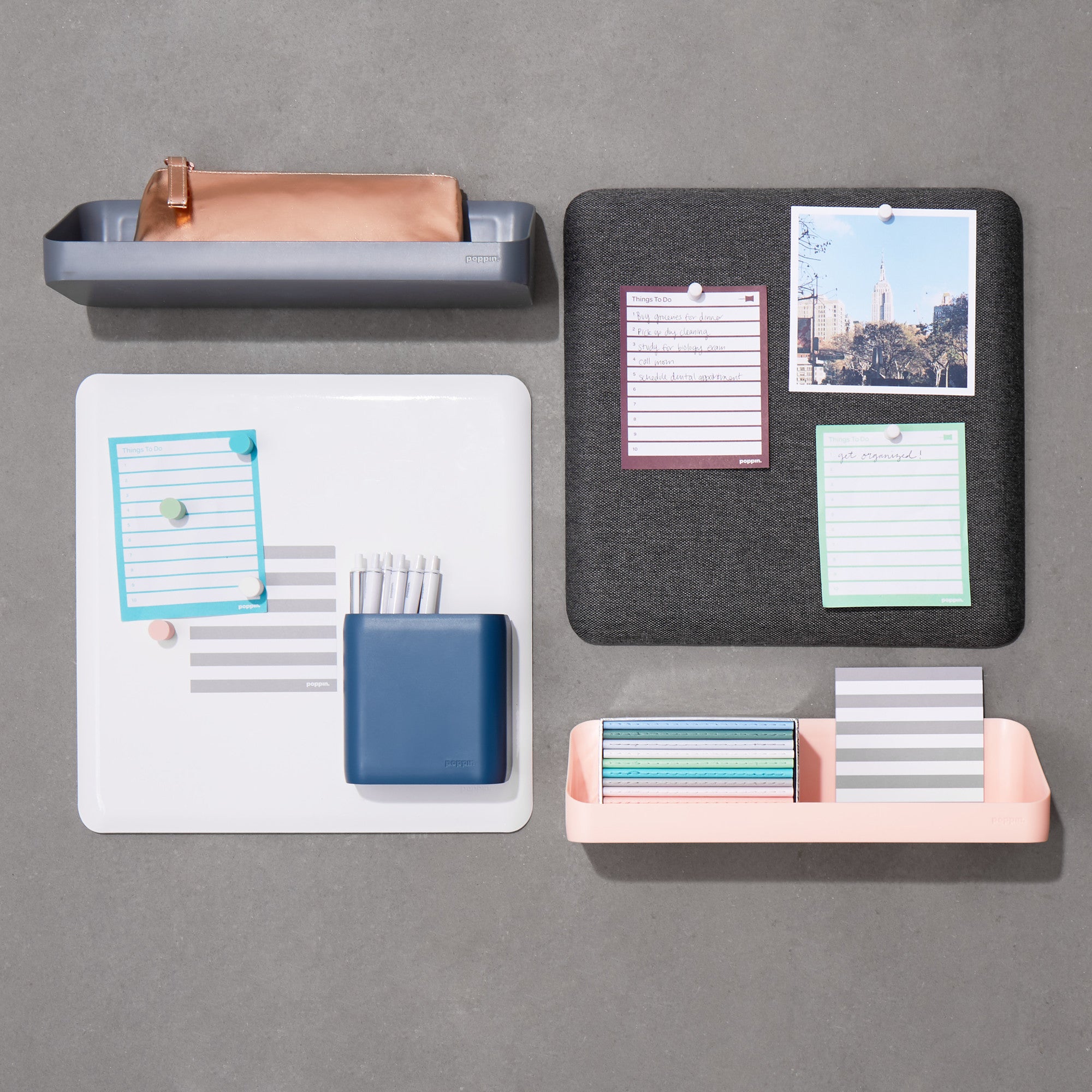Flat lay of organized desk accessories with notepads, stationery, and a passport on a grey background. 