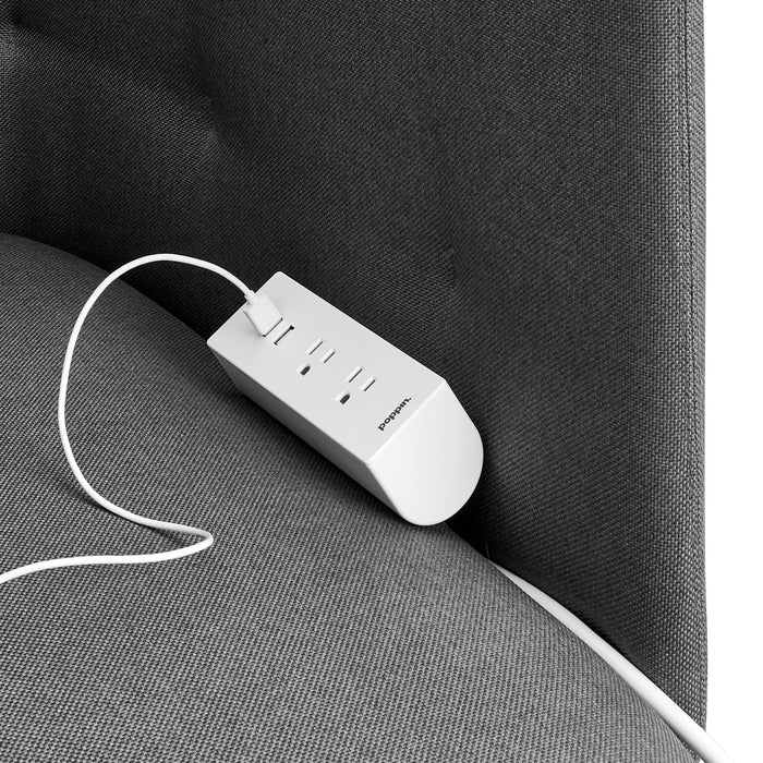 White power bank with cable on dark gray sofa fabric. 