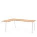 L-shaped wooden office desk with white legs on a white background. (Natural Oak)